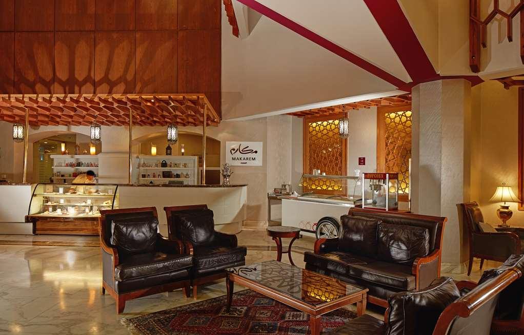 Makarem Ajyad Makkah Hotel Мекка Интерьер фото The photo shows a stylish interior of a lobby or lounge area. It features a seating arrangement with dark leather armchairs and a wooden table in front of them. The decor includes an intricate ceiling design and decorative wall elements that add a wa