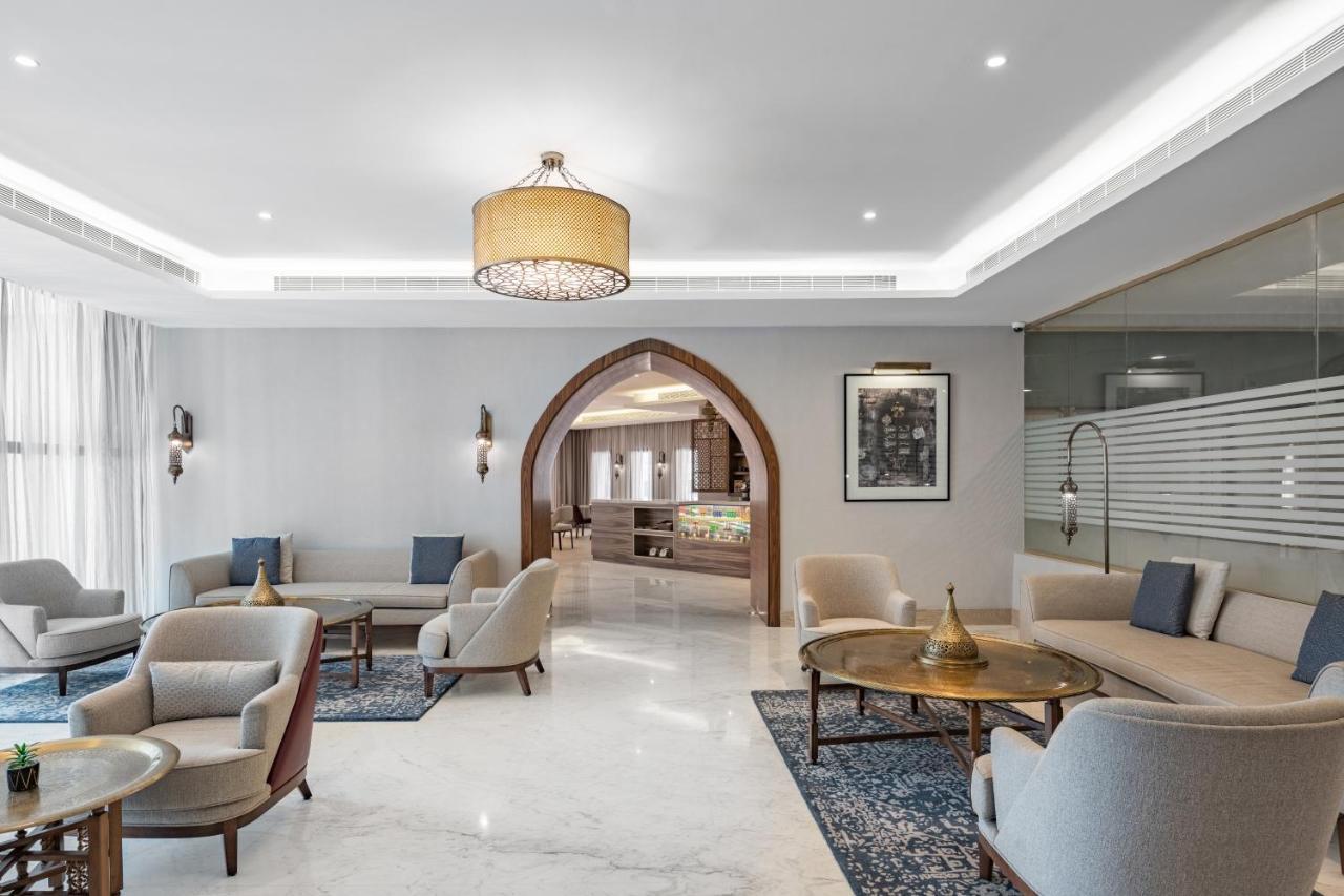 Makarem Ajyad Makkah Hotel Мекка Экстерьер фото The photo shows a modern and elegantly designed lounge area. It features light-colored walls and marble flooring, complemented by stylish furniture including several armchairs and small tables. The lighting is soft, provided by a decorative chandelie