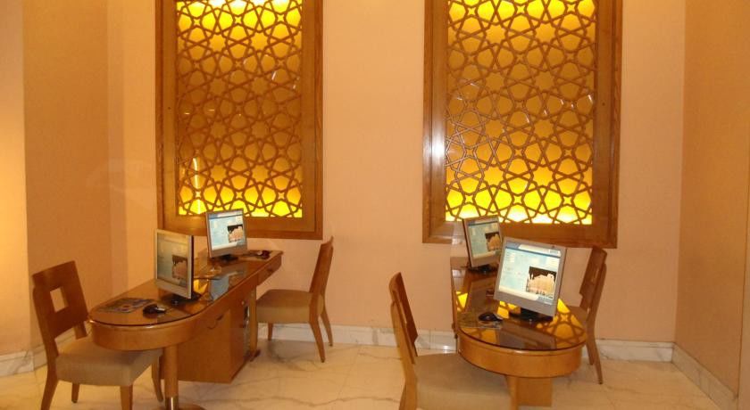 Makarem Ajyad Makkah Hotel Мекка Экстерьер фото The image shows a room with a warm, inviting atmosphere, featuring two wooden desks equipped with computers. Each desk has a chair positioned in front of it. The walls are adorned with decorative panels that exhibit intricate patterns, illuminated by