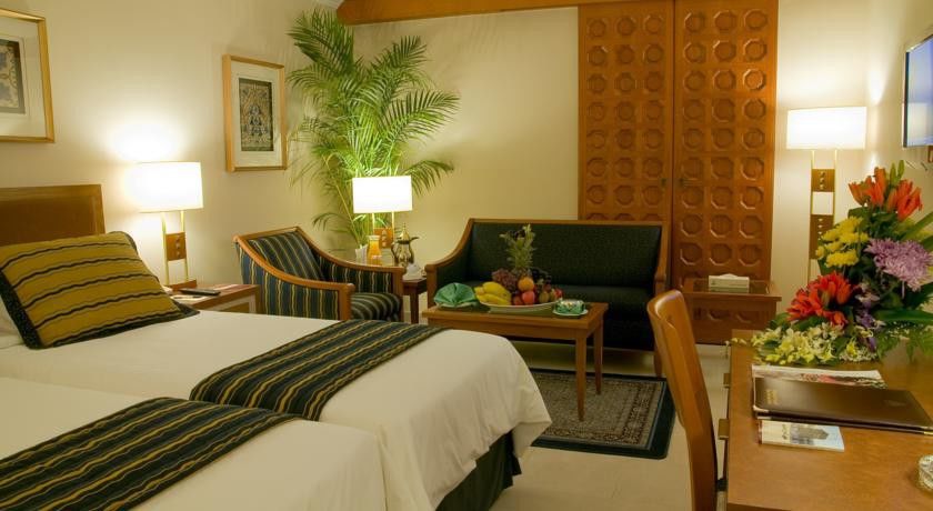 Makarem Ajyad Makkah Hotel Мекка Экстерьер фото The photo shows a cozy hotel room that features two single beds with white linens and dark green and striped blankets. There is a decorative rug on the floor. Against one wall, there is a large wooden partition with a distinctive geometric pattern. T