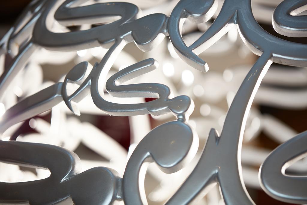 Makarem Ajyad Makkah Hotel Мекка Экстерьер фото The photo shows a close-up of a white, artistic structure or piece of decor that features intricate, stylized lettering. The letters are intertwined and have a fluid, modern design. The focus on the details reveals the elegance of the curves and shap